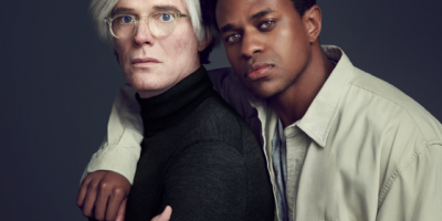 Paul Bettany as Andy Warhol crosses his arms. Jeremy Pope as Jean-Michel Basquiat leans against Bettany with an arm slung around his shoulders.
