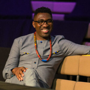 Kwame Kwei-Armah sits in a theatre, smiling.